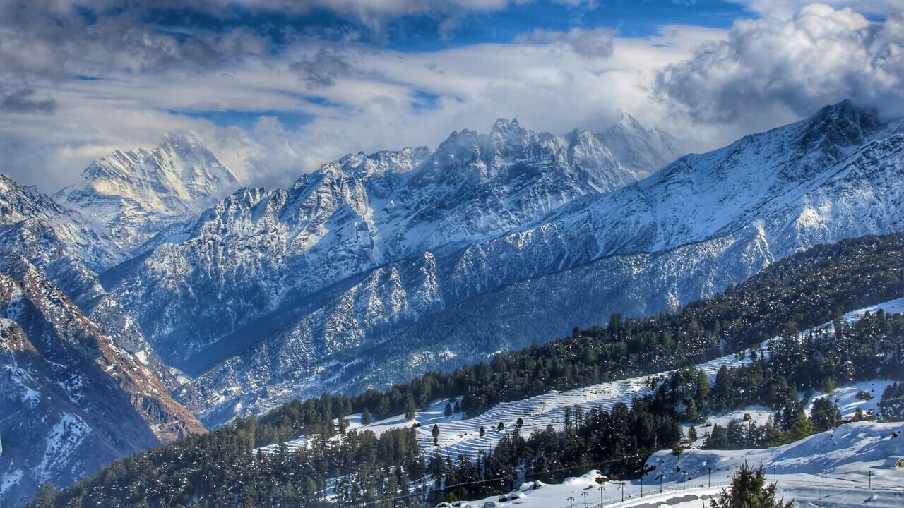 scenic view of mountain and trees in auli covered in snow