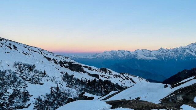 stunning sunset behind mountains covered in snow in chamoli