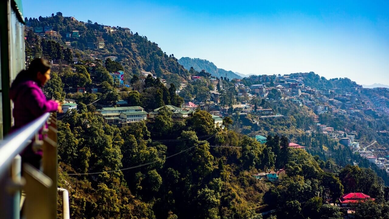 woman standing in balcony admiring the view of mussoorie