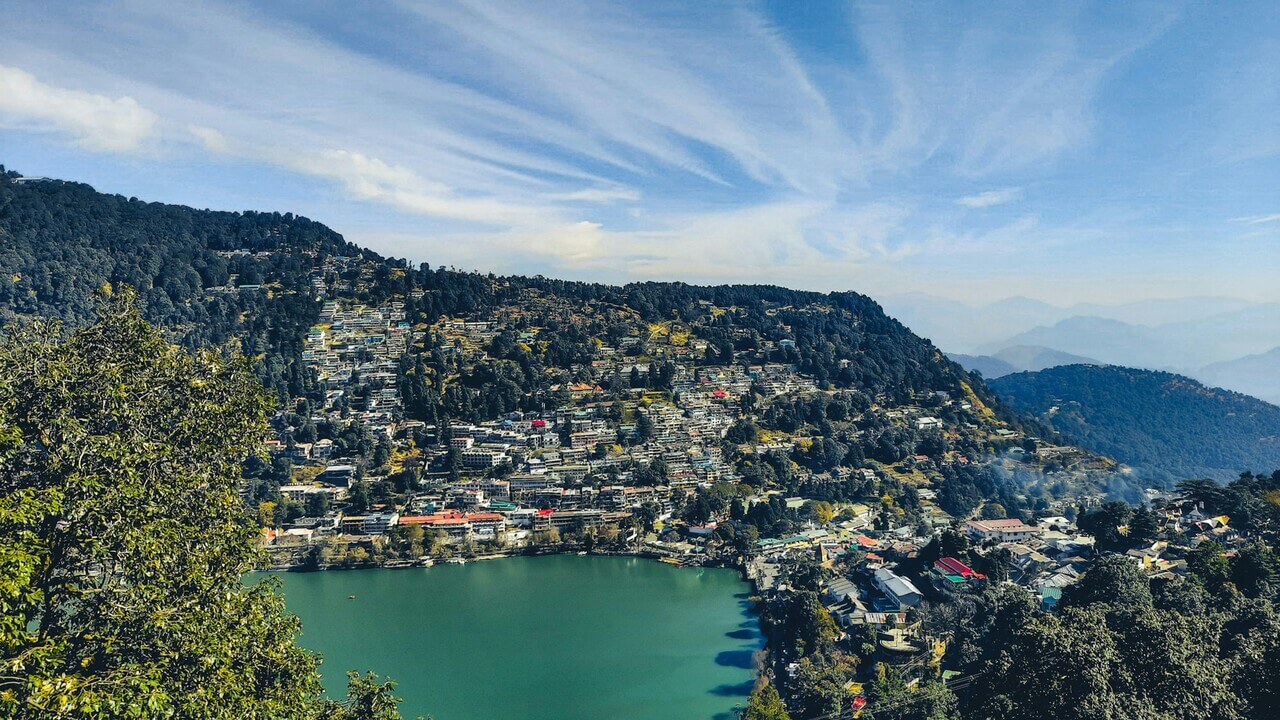 view of a lake surrounded by houses on hill in nainital