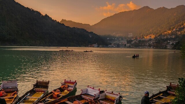 people boating in nainital enjoying view of a lake surrounded by houses on hill in nainitalsunset