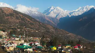 scenic mountain town with snowy mountain peaks in the distance in munsiyari